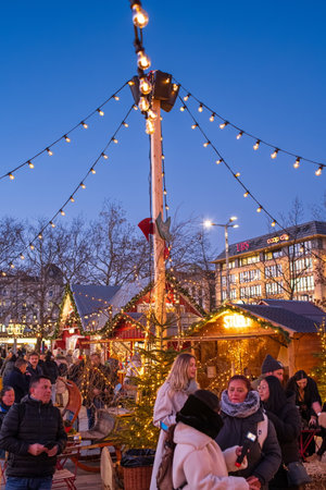 29-11-2024 Zurich, Switzerland. People attending the Christmas market at Sechselautenplatz. Evening light, blue sky, decorative Christmas light in the background.のeditorial素材