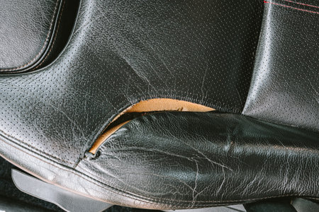 Torn, ripped, damaged car leather seat upholstery. Top down view, close up, no people.の写真素材