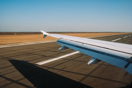 An airplane's left wing during landing, just a few meters in the air, above landing strip tarmac, no people.の写真素材