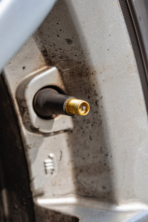 Car tire valve with no rubber cap. Close up macro shot, no people.