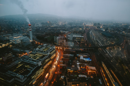 Aerial view of Zurich city on a gloomy, cloudy late evening. Car traffic light and train tracks, illuminated building and street light, no people.の写真素材