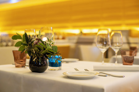 Empty table inside restaurant in the evening before start of service, Selective focus, shallow depth of field, interior lighting, no people, background blurの写真素材