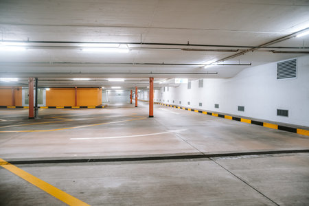 Empty, illuminated underground car parking lot. Wide angle view, no people, no cars.の写真素材