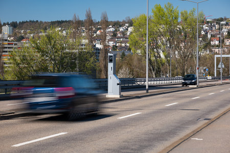 Blurry cares driving by a gray, mobile, car traffic speed trap camera between two car lane. Close up, telephoto shot.の写真素材