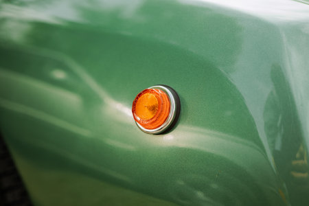Chrome ringed, orange, plastic side indicator or blinker on a green classic car. Close up shot, no people.の写真素材