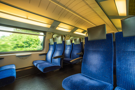 Empty blue cloth seats inside passenger train in Europe. Large window side seats, moving train,...
