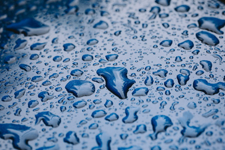 Water droplets on a blue car metal bodywork. Close up, macro shot, natural light, no people.の写真素材