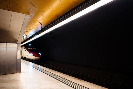 European intercity bullet train engine  with lit up lights. Moody, dark, underground train station, artificial ceiling lights, wide angle, no people.の写真素材