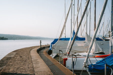 Docked sail boats in a shipyard or lake harbor in a town in Europe. Sunny summer day, wide angle, no people.の写真素材