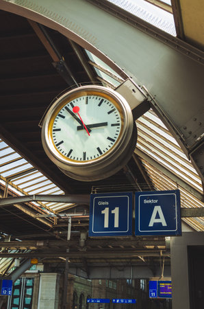 Large clock inside train main station in a European city. Looking up shot, platform number signs, no peopleの写真素材