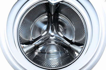 Puddle of water accumulated on the bottom of an empty washing machine drum. Wide angle view, bright, standing water, no peopleの写真素材