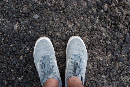 Top down view of classic casual sneakers on coarse, textures fresh asphalt backgroundの写真素材