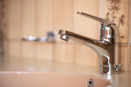 Dripping tap with inside apartment bathroom. Close up shot, shallow depth of field, no peopleの写真素材