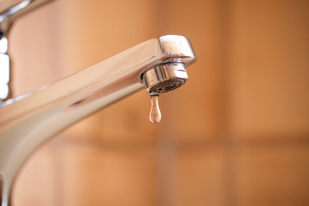 Dripping tap with water droplets inside apartment bathroom. Macro, close up shot, shallow depth of field, no peopleの写真素材