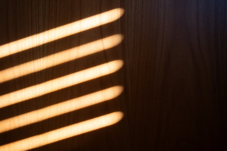 Sunlight streaks pattern projected on wooden wall by window roller shutters. Abstract background, no peopleの写真素材