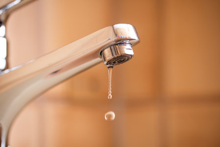 Dripping tap with water droplets inside apartment bathroom. Macro, close up shot, shallow depth of field, no peopleの写真素材