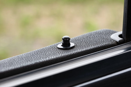 Car door lock knob or pin on the top of the door card. Close up, macro shot, shallow depth of field,...
