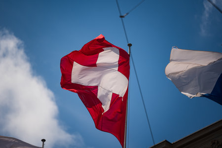 Swiss flag waving in the wind. Low angle view, close up shot, sunny summer day, looking up, telephoto shot, no peopleの写真素材