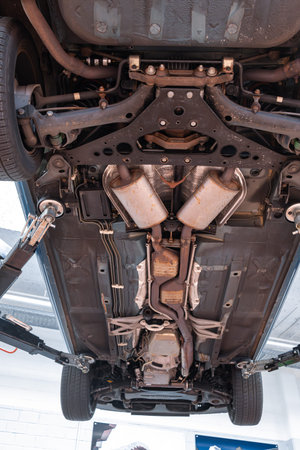Car undercarriage with exhaust system, wheels and axel components. Wide angle, looking up view, car...