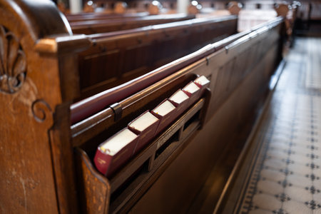 Small bible books in a shelf on the back of empty wooden pews inside church in Europe. Close up, wide angle shot, no peopleの写真素材