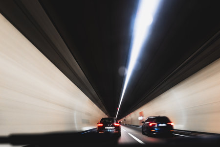 Blurry cars driving through a tunnel in Europe. Long exposure, artificial illumination, through the windshield point of view, no peopleの写真素材