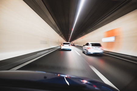 Blurry cars driving through a tunnel in Europe. Long exposure, artificial illumination, through the windshield point of view, no peopleの写真素材