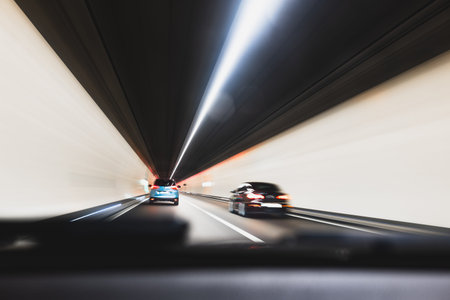 Blurry cars driving through a tunnel in Europe. Long exposure, artificial illumination, through the windshield point of view, no peopleの写真素材