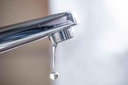 Dripping tap with water droplets inside apartment bathroom. Macro, close up shot, shallow depth of field, no peopleの写真素材