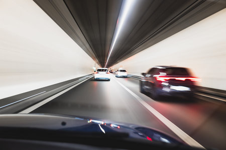 Blurry cars driving through a tunnel in Europe. Long exposure, artificial illumination, through the windshield point of view, no peopleの写真素材