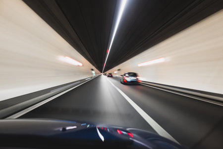 Blurry cars driving through a tunnel in Europe. Long exposure, artificial illumination, through the windshield point of view, no peopleの写真素材