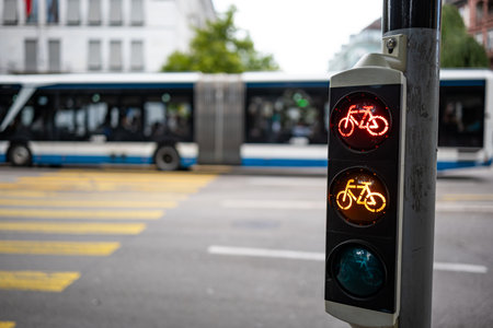 Bicycle traffic light next to pedestrian crossing, showing red and yellow. Close up, wide angle shot, shallow depth of field, blurry background and busの写真素材