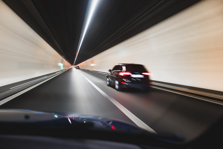 Blurry cars driving through a tunnel in Europe. Long exposure, artificial illumination, through the windshield point of view, no peopleの写真素材