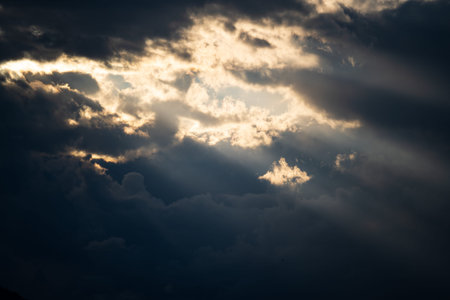 Sun light and rays breaking through thick storm clouds