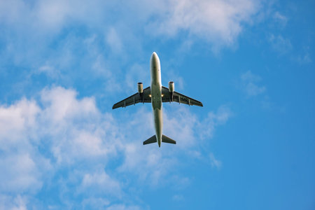 Commercial passenger plane belly or bottom as seen from the ground. Close up telephoto shot, blue sky background, no peopleの写真素材