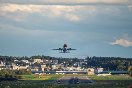 Commercial passenger plane taking off from a long runway, front view. Overcast summer day, runway...