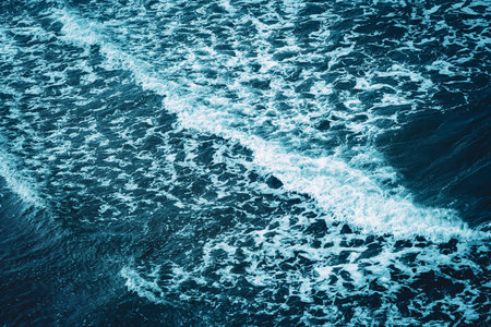 Foamy, shallow, tidal waves reaching the sandy shore. Top down view, shallow water, aqua blue cold...