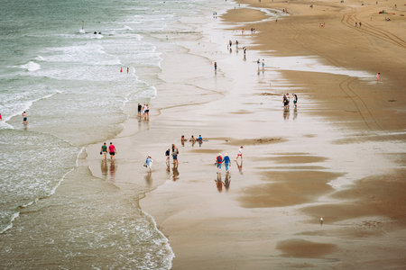 People at a seaside beach enjoying the last days of summer. Wide angle, above view, small waves on the shoreの写真素材