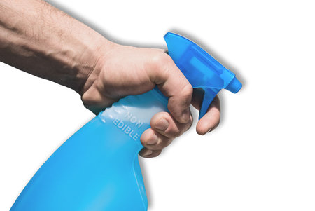A man's  hand holding a spray bottle of cleaning stuff.