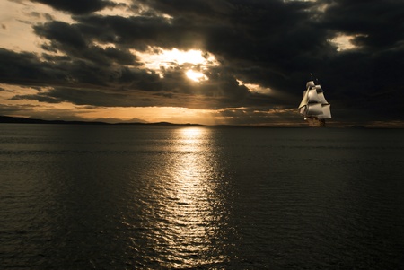 A sailboat drifts on the water at sunsetの写真素材