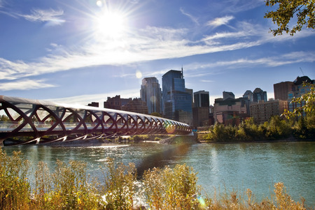 A pedestrian bridge accross  Bow River in Calgary with skyscrapers in the background.の写真素材
