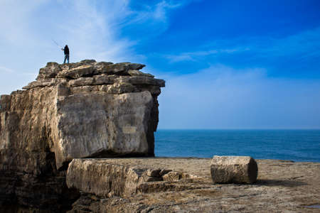 Fisherman fishing on the coast cliffの写真素材
