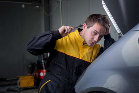 Portrait of handsome mechanic based on car in auto repair shop smilingの写真素材