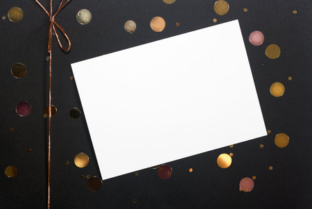 Note or greeting card, golden confetti and ribbon bow on black box background. Gift conceptの写真素材