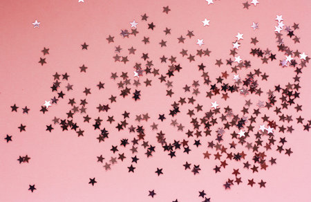 Silver stars glitter against pink background. Festive sparkling background.