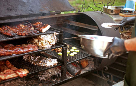 Man cooks different kinds of meat and vegetables on the grill outdoors in the summerの写真素材