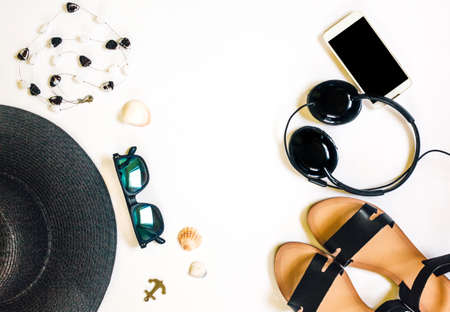 Travel female accessories phone, earphones, sunglasses, sandals, necklace and hat on white background for summer holiday and vacation concept.の写真素材