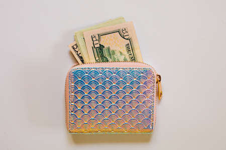 Trendy holographic purse with dollar banknotes on white background. Flat lay, top view.の写真素材