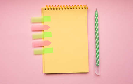 Blank page of vertical spiral note pad with pen on pink background, flat lay. Office accessories. Back to school.の写真素材