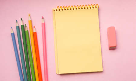 Blank page of vertical spiral sketching pad with crayons on pink background, flat lay. Back to school.の写真素材