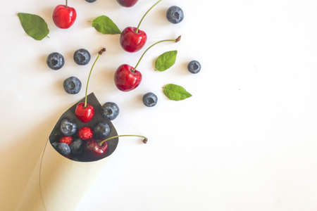 Summer Berries against White Background in the paper cone. Top view, flat lay. Blueberry, raspberry and cherry fresh berries.の写真素材